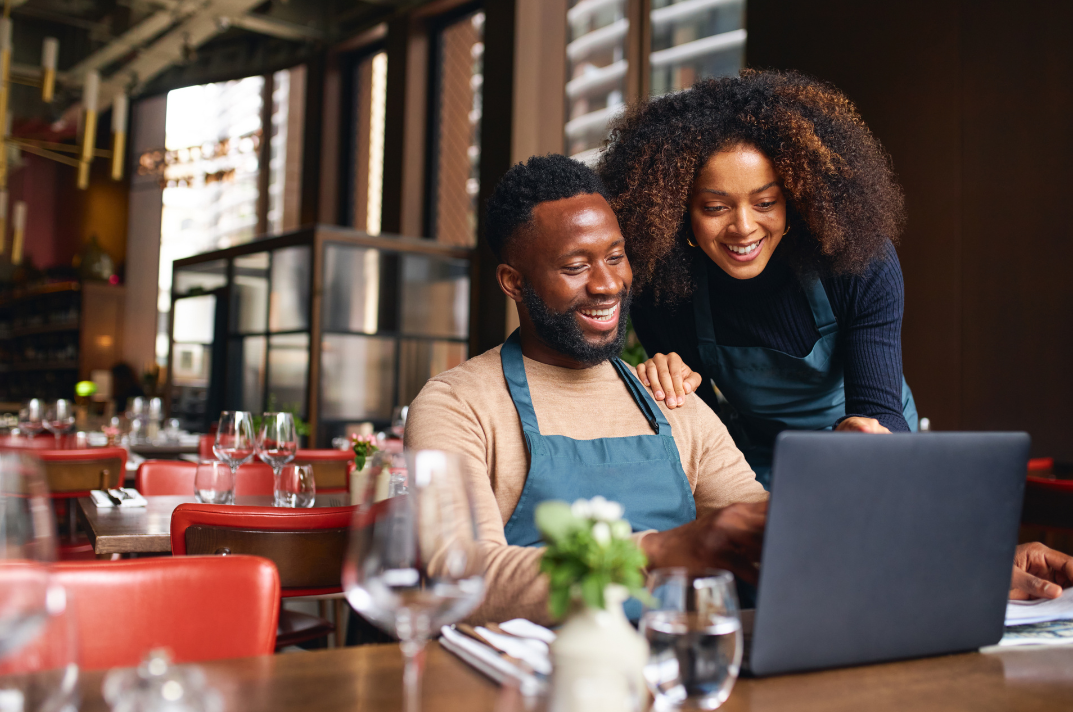 Restaurant owners reviewing their business on a laptop together